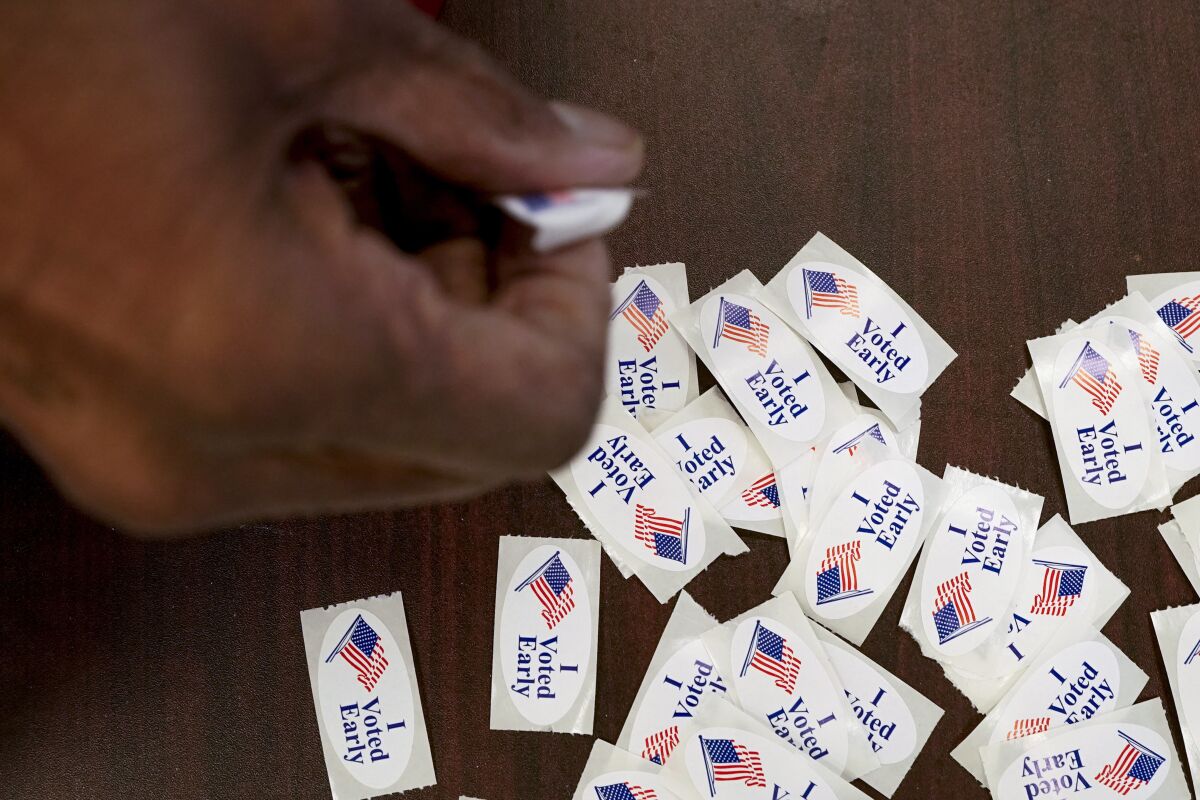 A hand takes a sticker after casting an early ballot at a polling station.