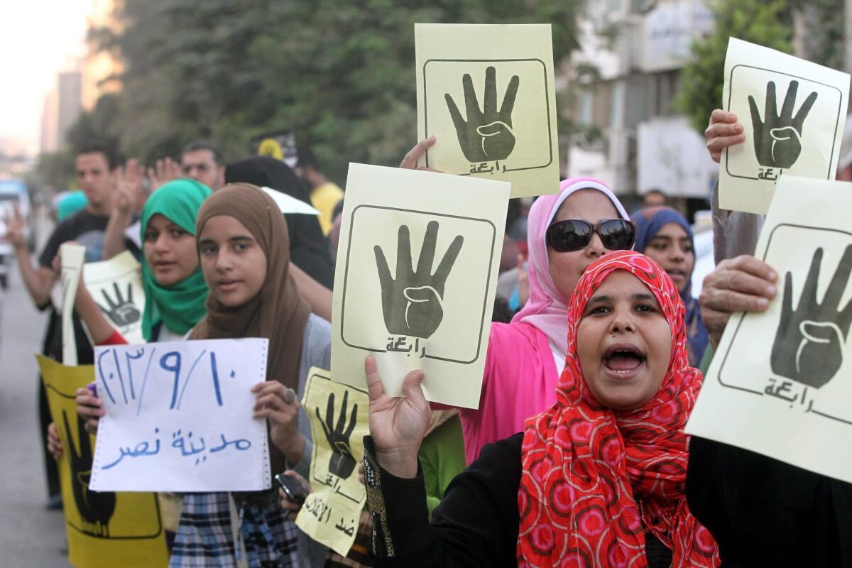During a protest in Cairo, supporters of ousted President Mohamed Morsi hold posters with a hand in a sign of the number four, a reference to a mosque where troops cracked down on demonstrators last month.