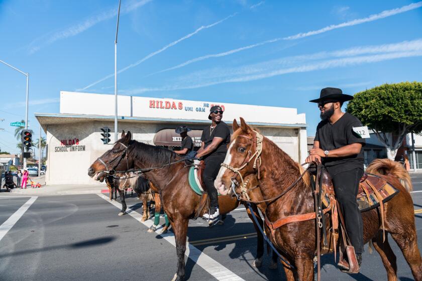Compton Cowboys members Charles Harris and Randy Hook are sitting on their horses during the middle of the Compton Christmas Parade. Credit: Walter Thompson-Hernandez