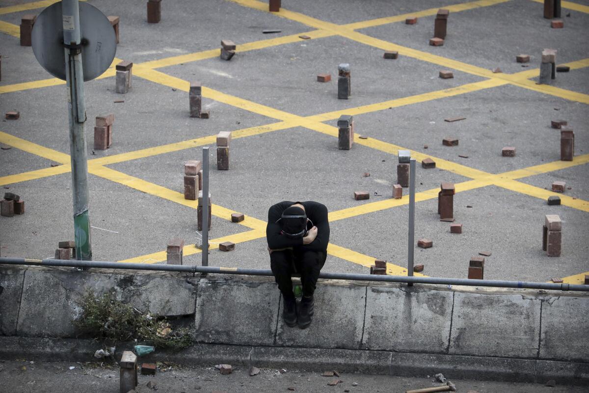 A protester sits near stacks of bricks that were used to barricade a road Nov. 14 near Hong Kong Polytechnic University.