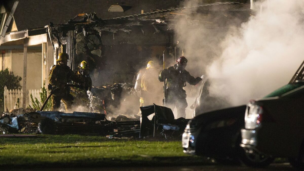 Firefighters battle heavy smoke after a plane crashed into houses on Rhonda Road in Riverside. Three people were killed.