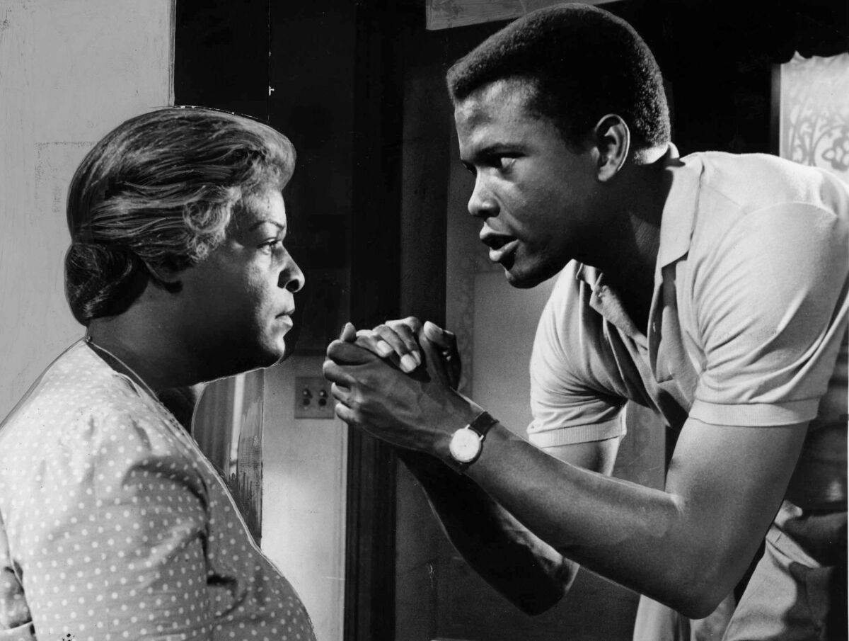 Sidney Poitier, with hands clasped, stands before a seated Claudia McNeil in a black and white image.