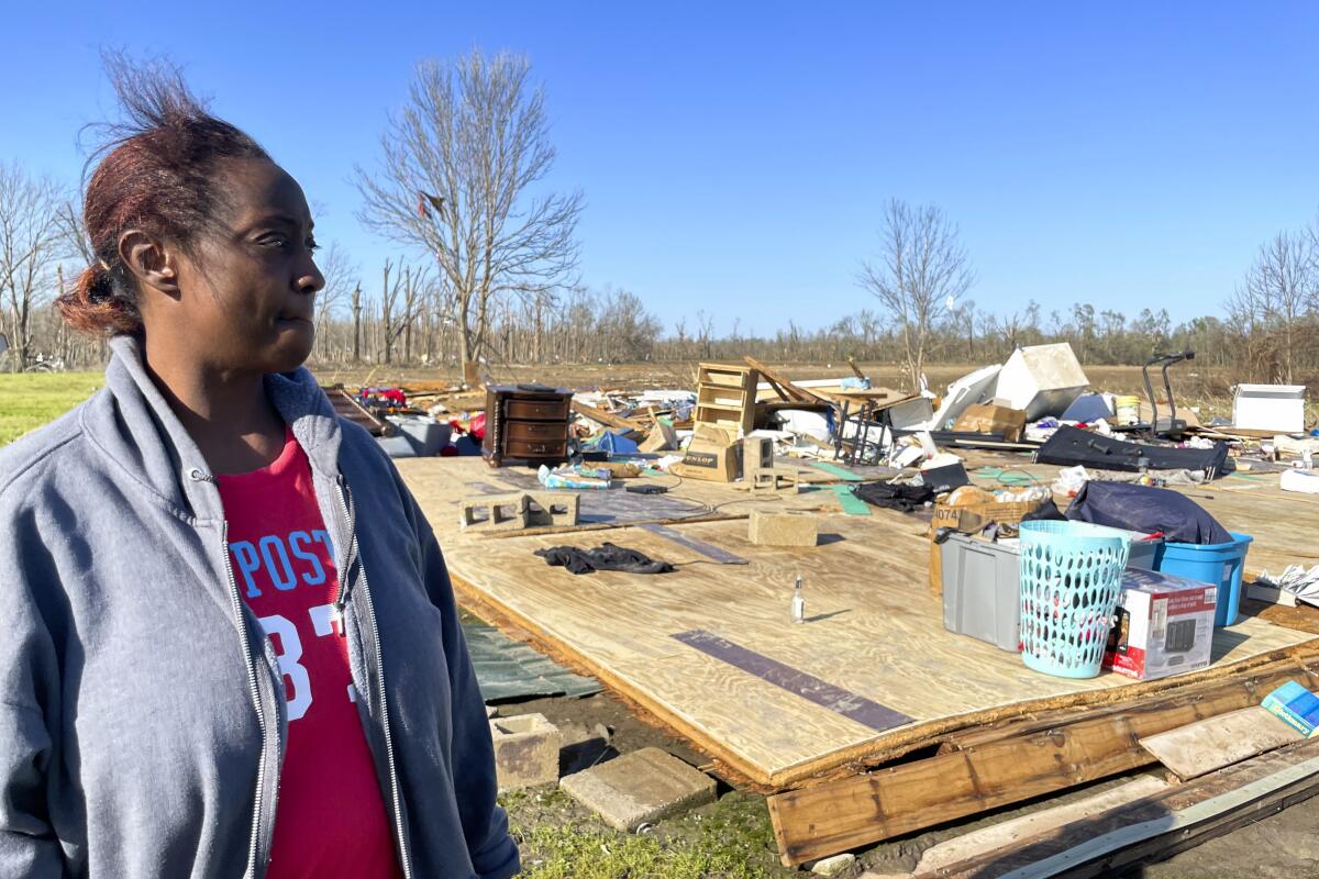 A woman looks at her home destroyed by a tornado.