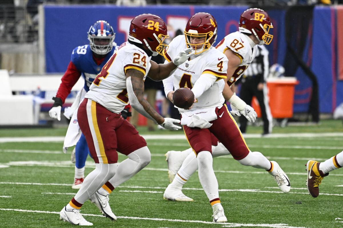 Washington Football Team quarterback Taylor Heinicke hands off to running back Antonio Gibson.