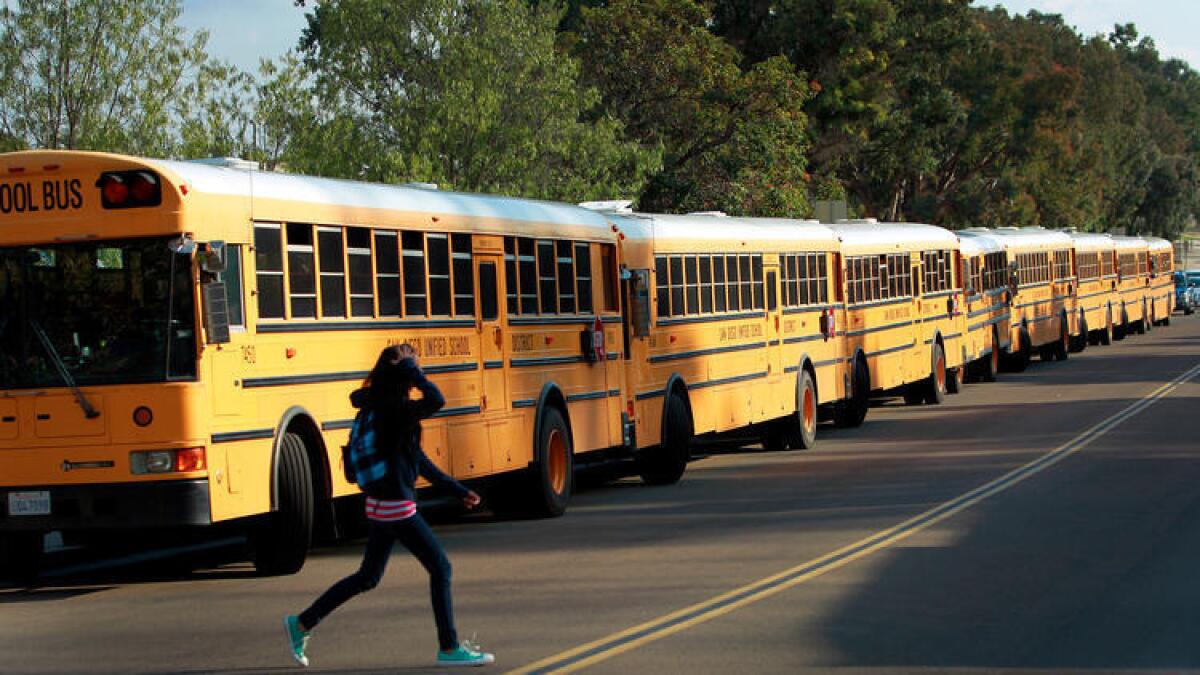 Los autobuses escolares hacen fila mientras los estudiantes de San Diego School of Creative and Performing cruzan la calle en 2011.
