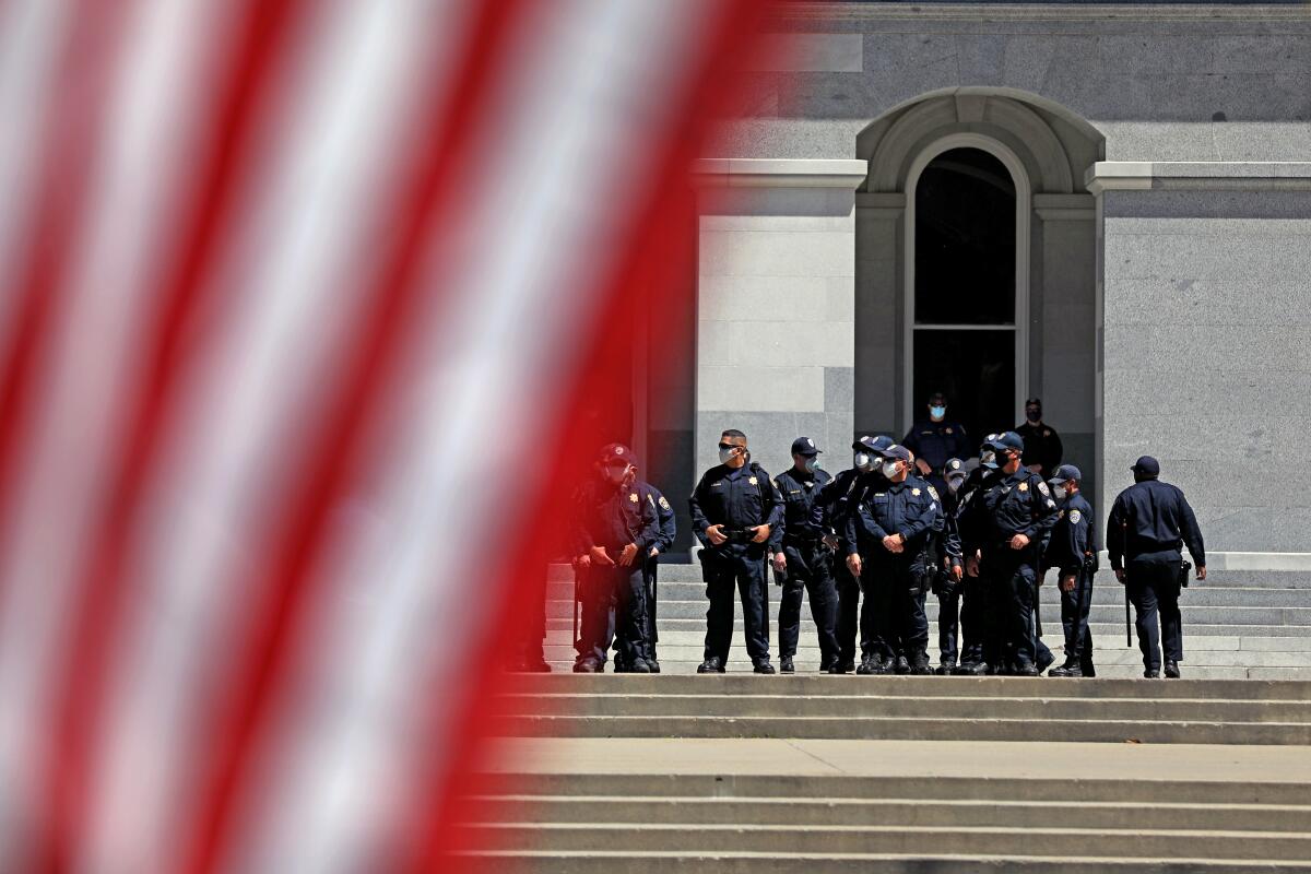 Sacramento police stand guard as a crowd gathers for Saturday's rally.