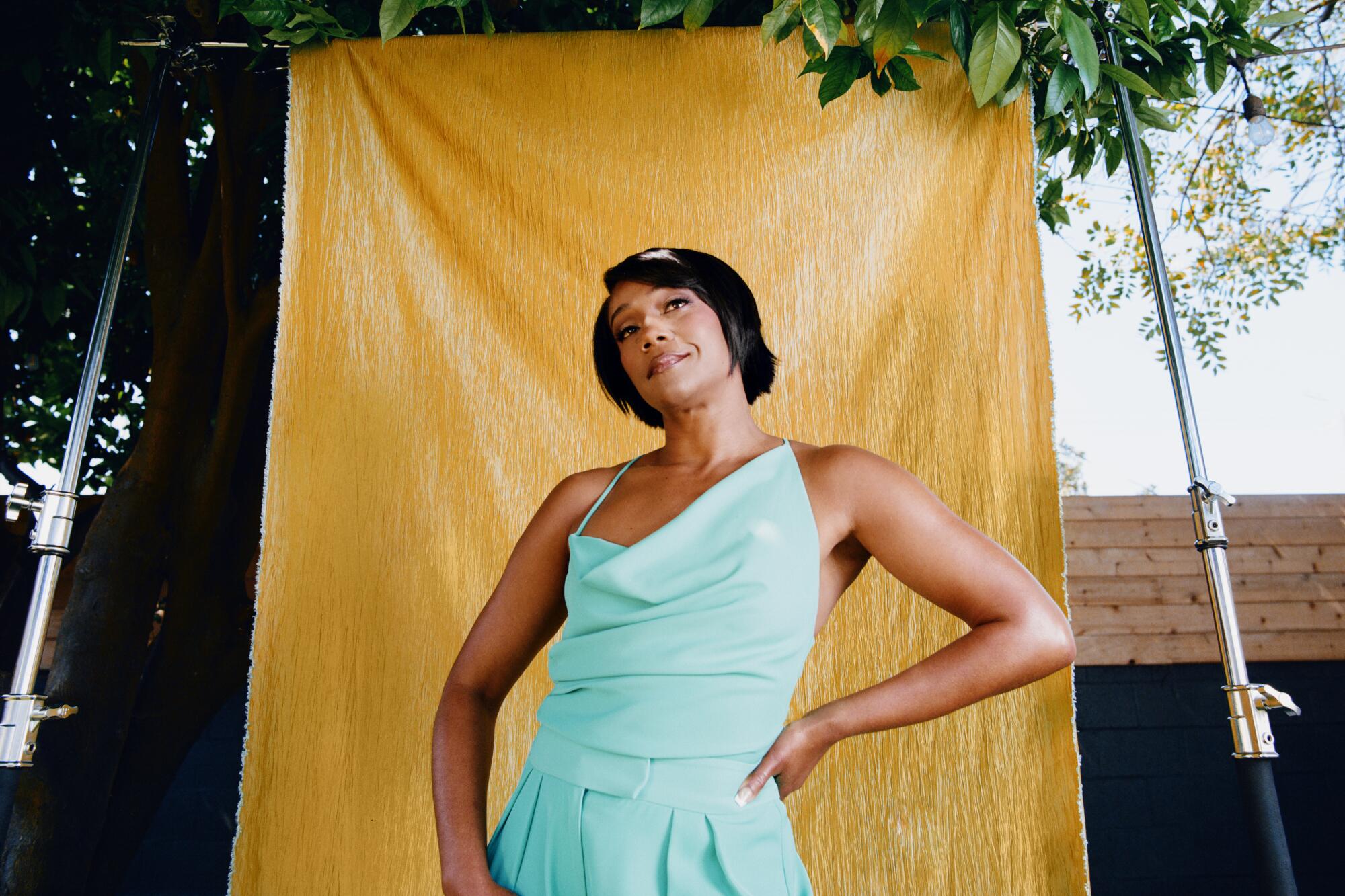  Tiffany Haddish, in a mint green dress, stands before a mustard-yellow backdrop outdoors.