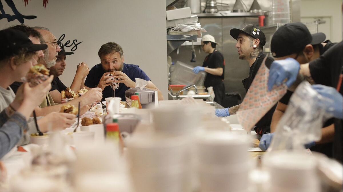 Phil Rosenthal, rear left, of Netflix's "Somebody Feed Phil," gets his hands on the Medium Plus spicy fried chicken sandwich at Howlin' Ray's.