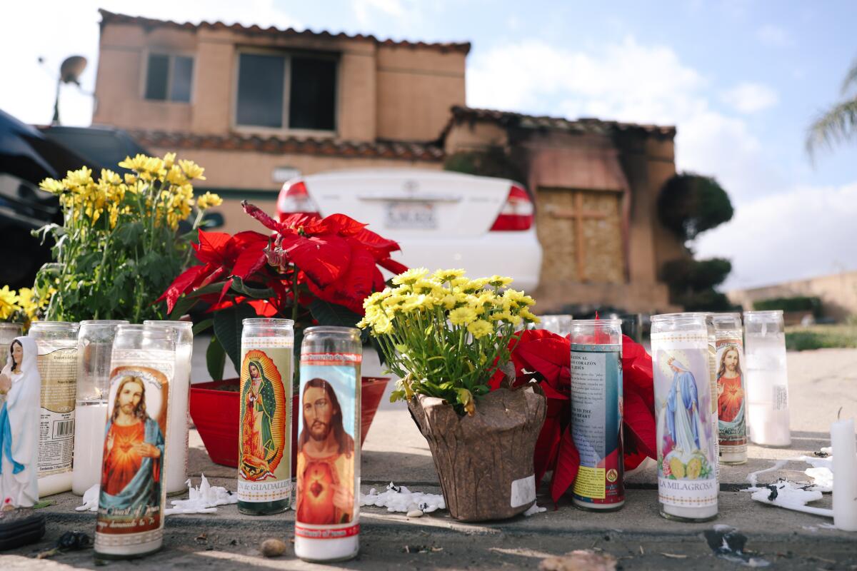 Candles and flowers in front of a burned home