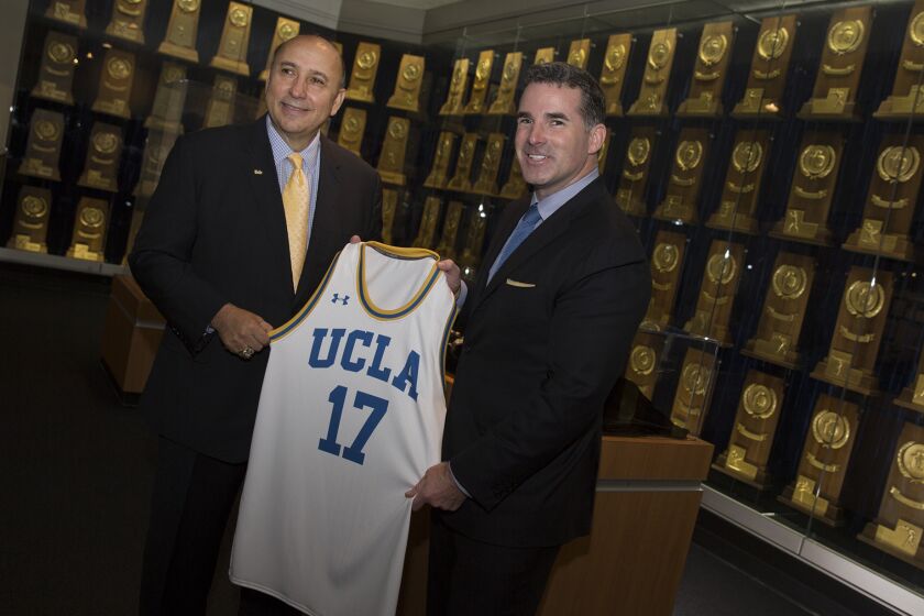 UCLA athletic director Dan Guerrero, left, and Under Armour's Kevin Plank with a UCLA jersey following a meeting and prior to a press conference at the Morgan Center where they officially announced UCLA and Under Armour agreement