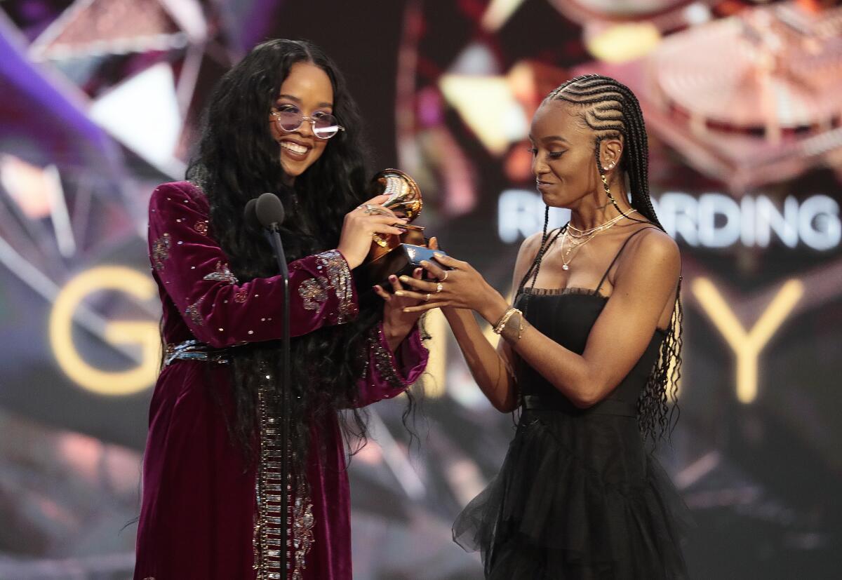 H.E.R. and Tiara Thomas hold a Grammy.