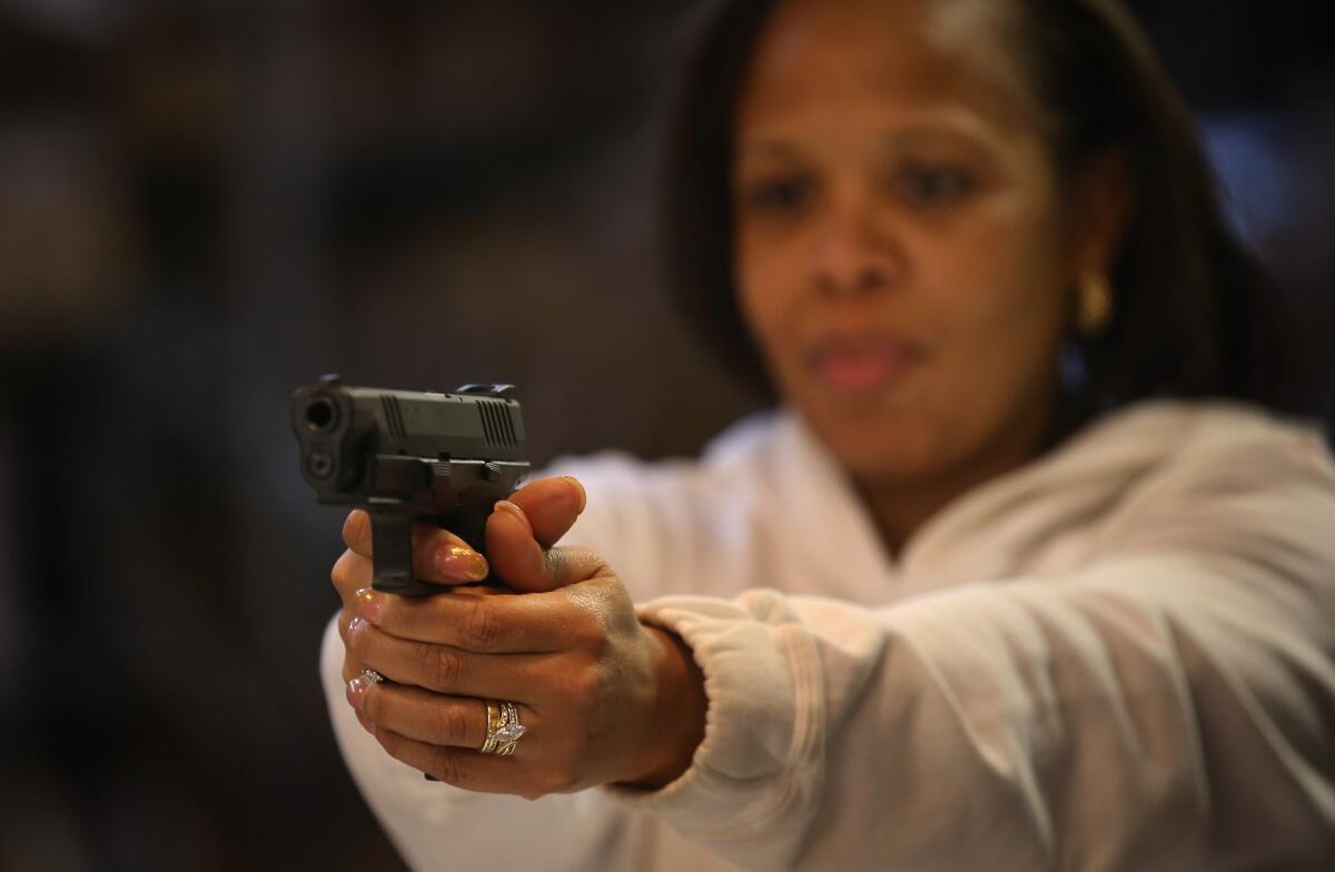 Cheryl Bourgeois learns how to fire a pistol during an NRA Basic Pistol Course at Freddie Bear Sports sporting goods store in Tinley Park, Ill.