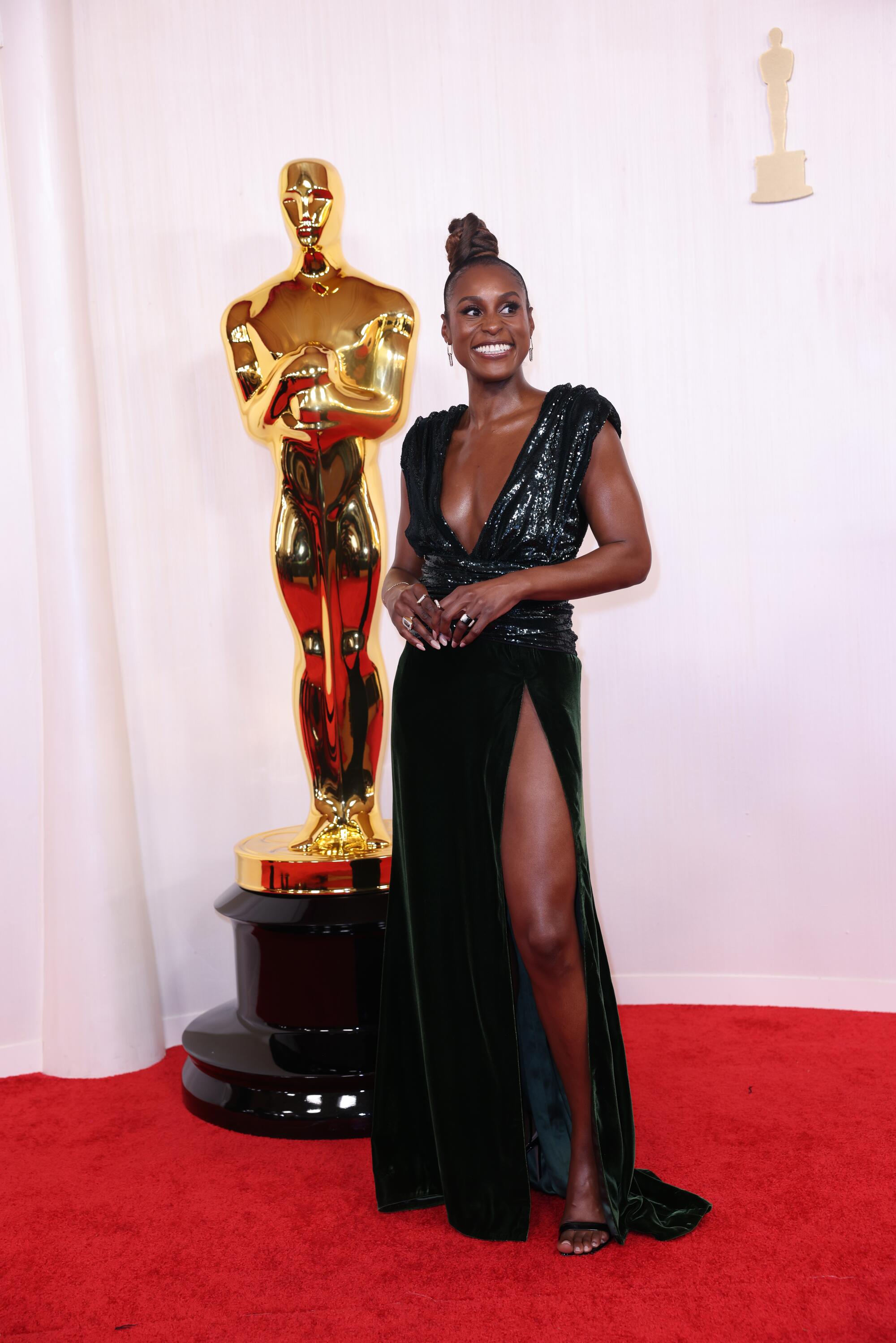 Issa Rae wears a sequined deep green gown with a plunging neckline. 