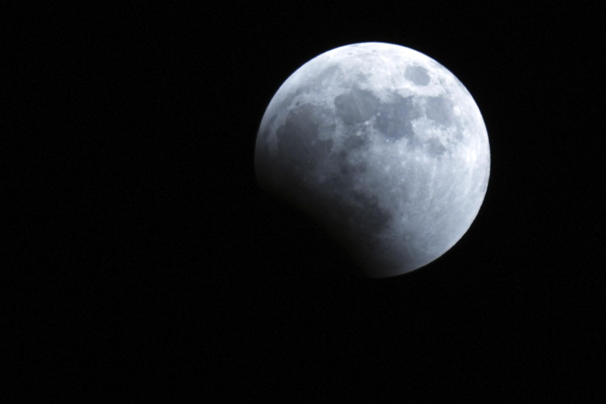 The Earth's shadow starts to cover the moon during a lunar eclipse in Yokohama near Tokyo.