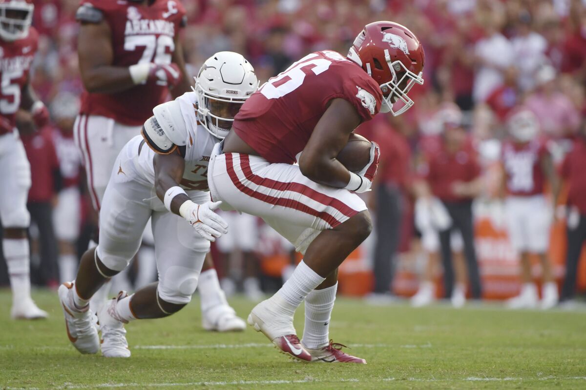 Texas defender Jaylan Ford (41) tackles Arkansas receiver Treylon Burks (16) during the first half of an NCAA college football game Saturday, Sept. 11, 2021, in Fayetteville, Ark. (AP Photo/Michael Woods)