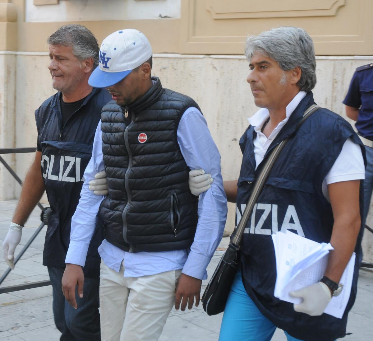 Mourad Botaib is taken to police offices in Palermo, Italy, on Friday. Prosecutors in Sicily detained 10 people on suspicion of smuggling and murder Friday for having allegedly crammed dozens of migrants into the airless hold of a boat where 52 bodies were found this week.