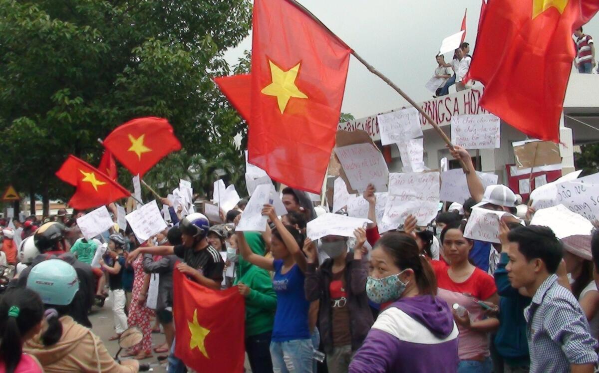 Protesters wave flags and hold placards on a street outside a factory in Binh Duong on Wednesday as anti-China protesters set more than a dozen factories on fire in Vietnam, according to state media.