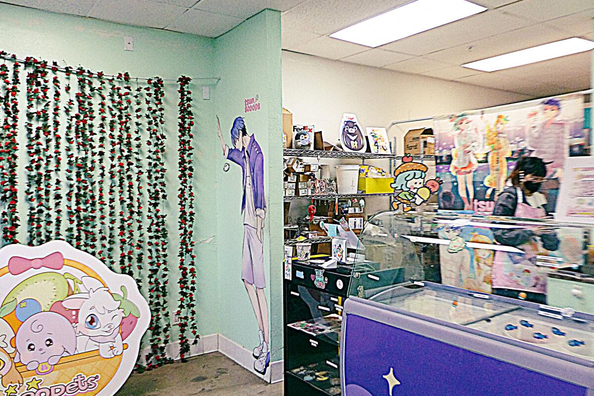 A store with walls with painted-on characters and strands of roses is next to an ice cream cooler.