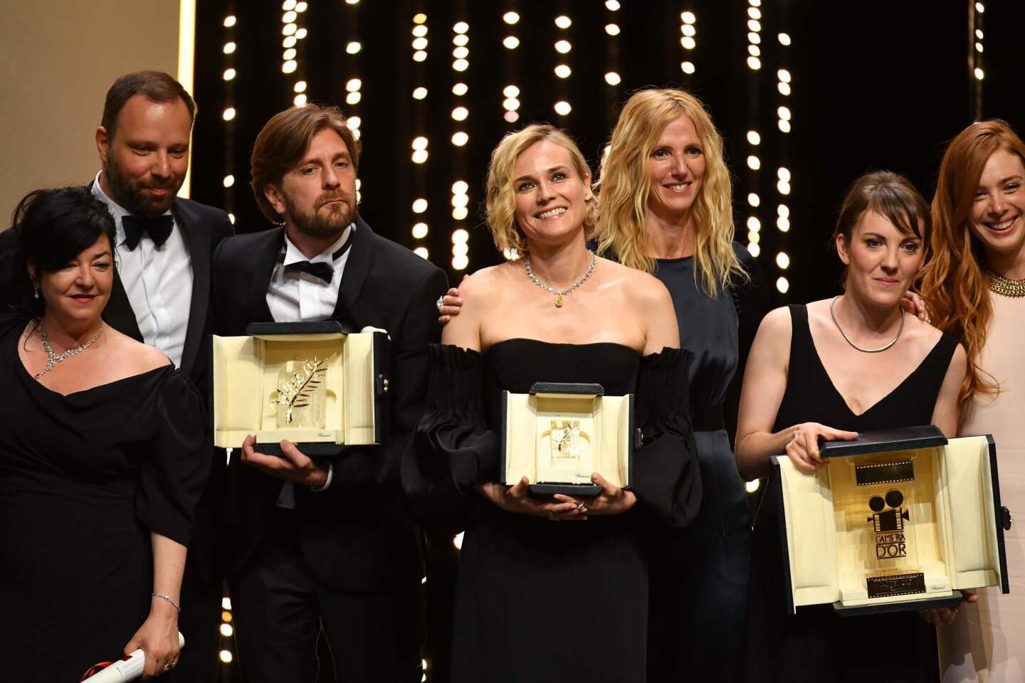 Best screenplay co-laureates directors Lynne Ramsay and director Yorgos Lanthimos, Palme d'Or laureate director Ruben Ostlund, best actress prize laureate Diane Kruger, actress and President of the Camera d'Or jury Sandrine Kiberlain, Camera d'Or laureate director Leonor Serraille and actress Laetiti Dosch pose on stage at the end of the closing ceremony.