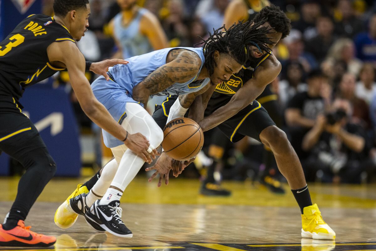 Memphis Grizzlies guard Ja Morant dribbles the ball as he is defended by Golden State Warriors guard Jordan Poole, left, and forward Andrew Wiggins during the fourth quarter in Game 3 of an NBA basketball playoffs Western Conference semifinal, Saturday, May 7, 2022. (Stephen Lam/San Francisco Chronicle via AP)