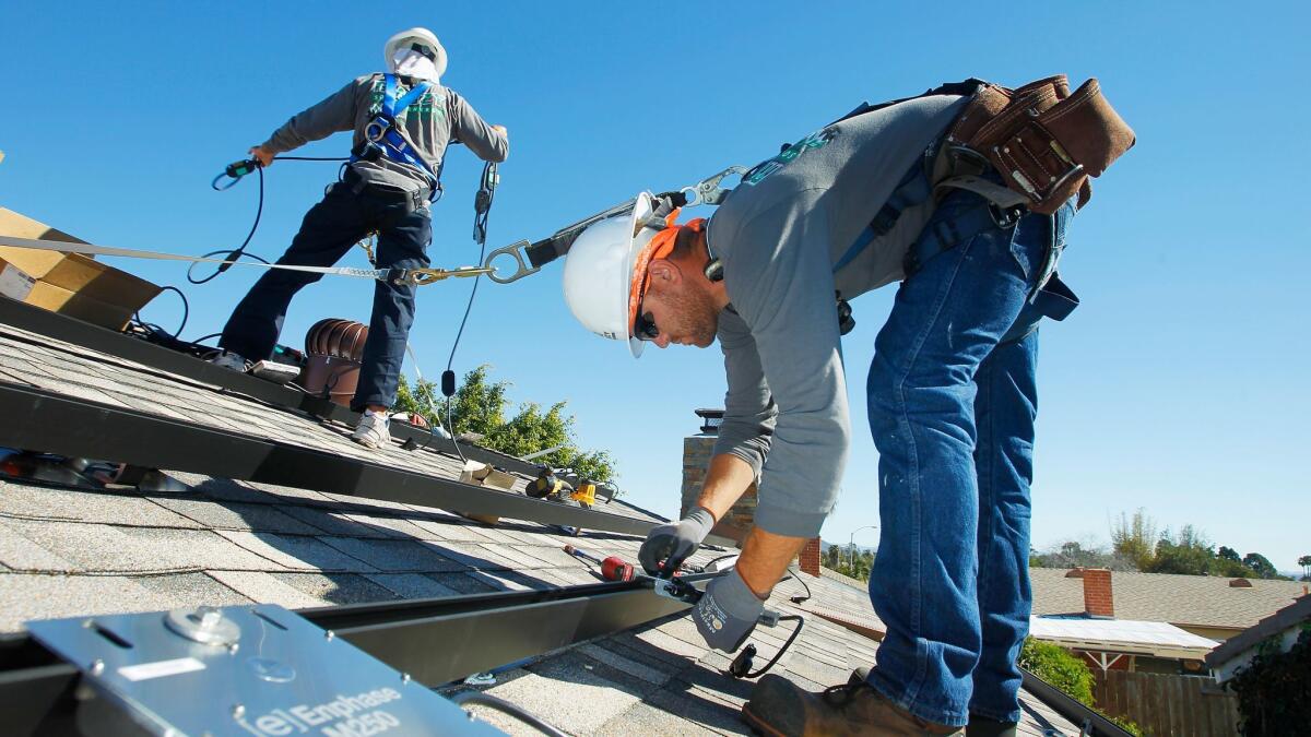 Workers install solar panels on the roof of a house in Serra Mesa.