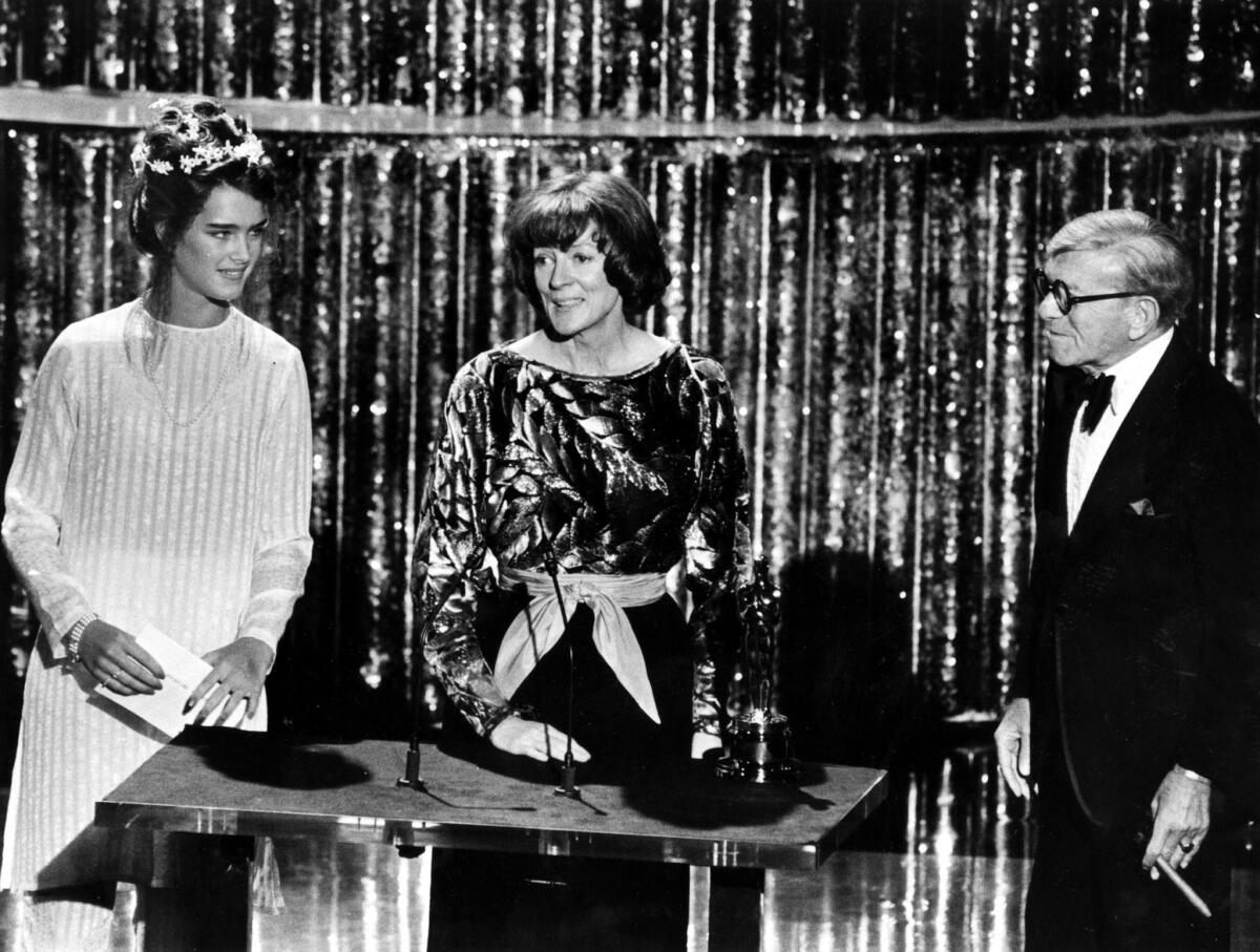 Two women and a man dressed up at a podium onstage.