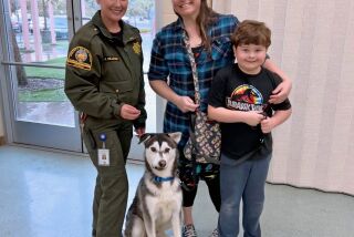San Diego County Department of Animal Services Lt. Joy Ollinger stands with Sherry Lankston and her son Harrison as they adopt Harvey and prepare to road trip home to Seattle.