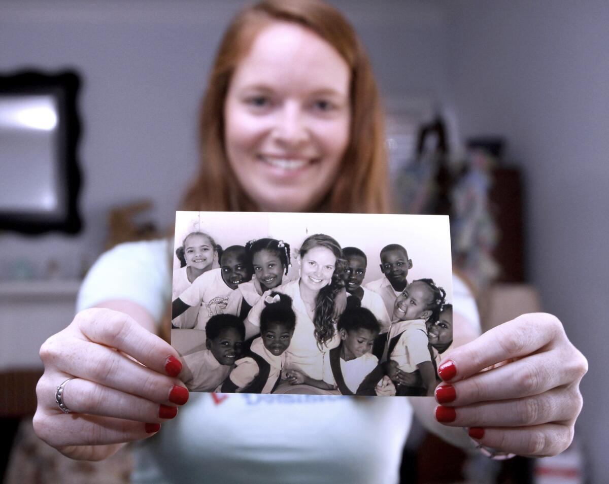 Molly Roach, 24, a Crescenta Valley High School alumnus who has been teaching English to Haitian students in the Dominican Republic, shows a photo of herself with some of her Haitian students at her home in Glendale on Wednesday, April 30, 3014. Roach has been traveling to the Dominican Republic through her church since age 16 and lived there for two years from 2011 through 2013.