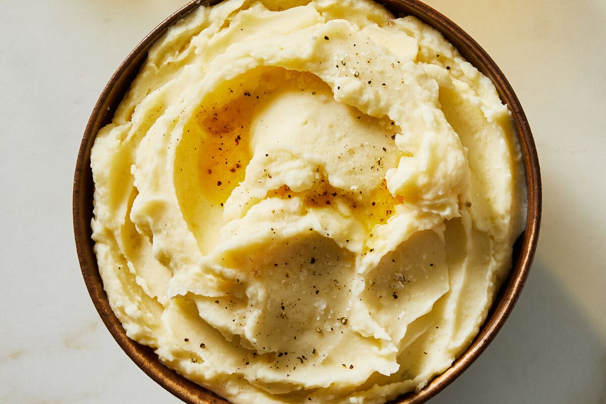 Mashed potatoes are served in a bowl topped with black pepper.