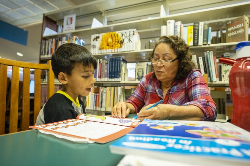 A woman tutors a boy inside a library
