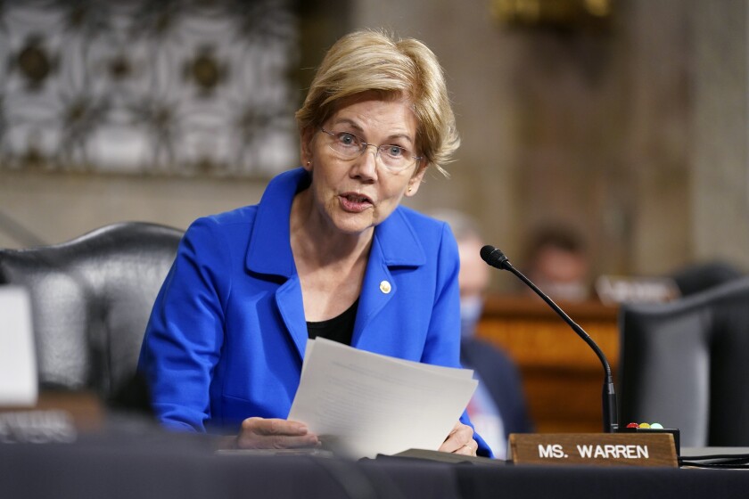 Sen. Elizabeth Warren holds sheets of papers while speaking into a microphone. 