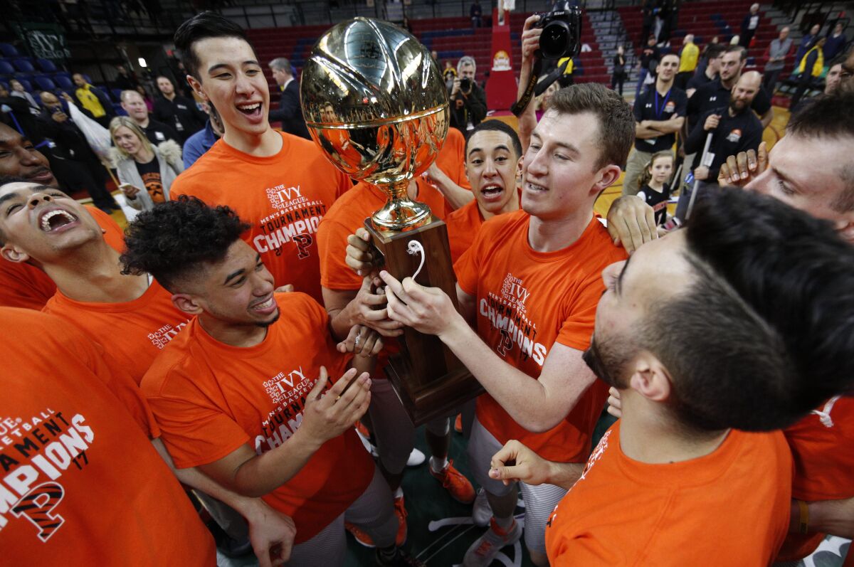Princeton gather arounds the Ivy League Basketball Tournament Trophy following the championship game.