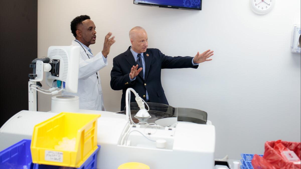 Dawit Mengesha shows Coffman the Precision Clinical Laboratories facilities in Aurora, Colo. on Feb. 21.