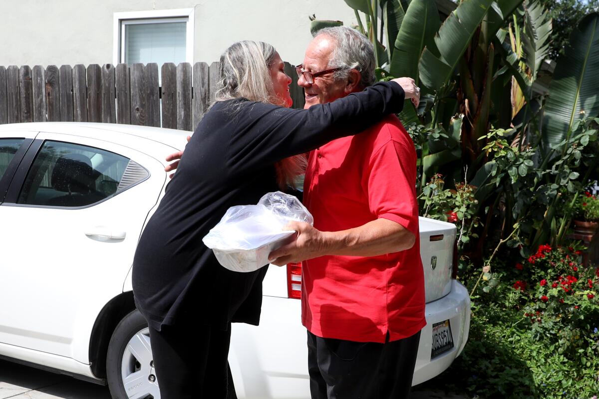 Jodi Sisson hugs Giovanni Bolla as he delivers a tiramisu to her in Lake Balboa.