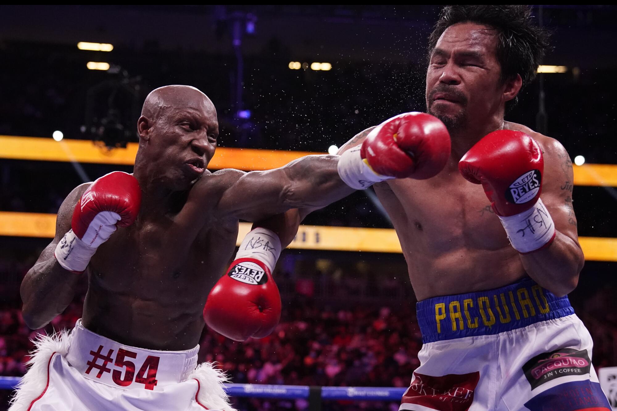 Yordenis Ugas, left, of Cuba, hits Manny Pacquiao, of the Philippines.
