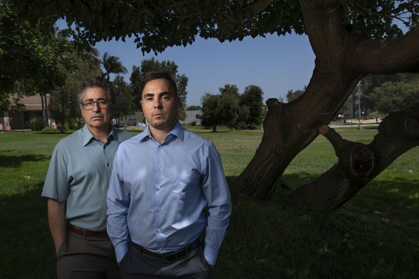 LOS ANGELES, CA -JULY 10, 2020: Attorney V. James DeSimone, left, is photographed with his client Daniel Garza at Westchester Park in Los Angeles. A jury in 2017 found in favor of Garza after he sued LAPD police officer Mario Cardona for using excessive force, detaining him without cause during an altercation in 2015, awarding him more than $200,000. He has yet to receive a penny, after the city refused to indemnify Cardona, and Cardona filed for bankruptcy. (Mel Melcon / Los Angeles Times)