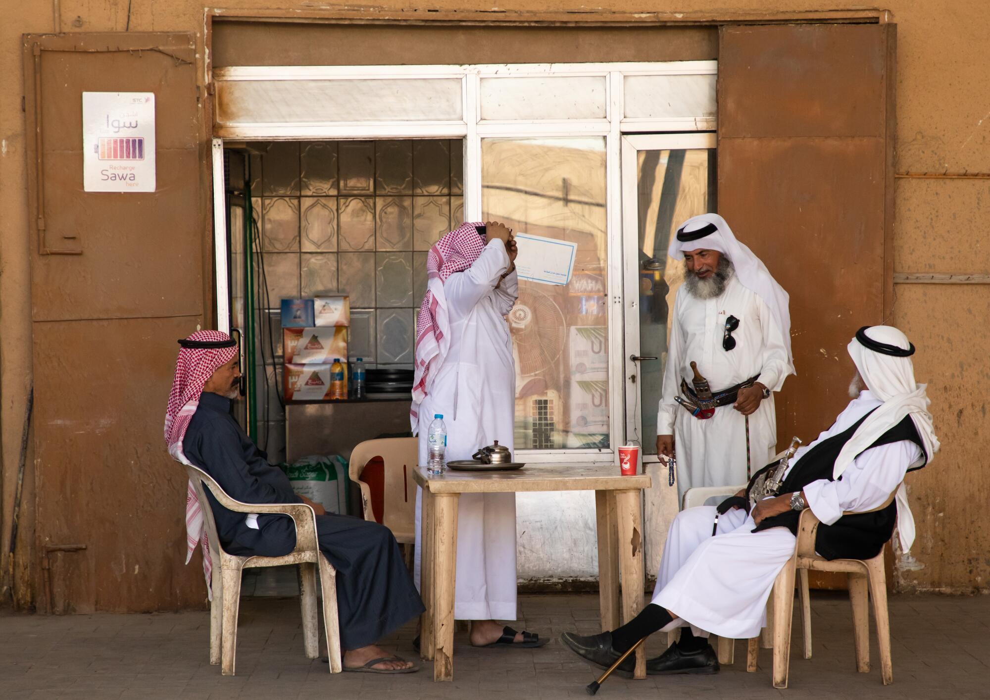 Saudi men gather at an outdoor table to drink coffee.