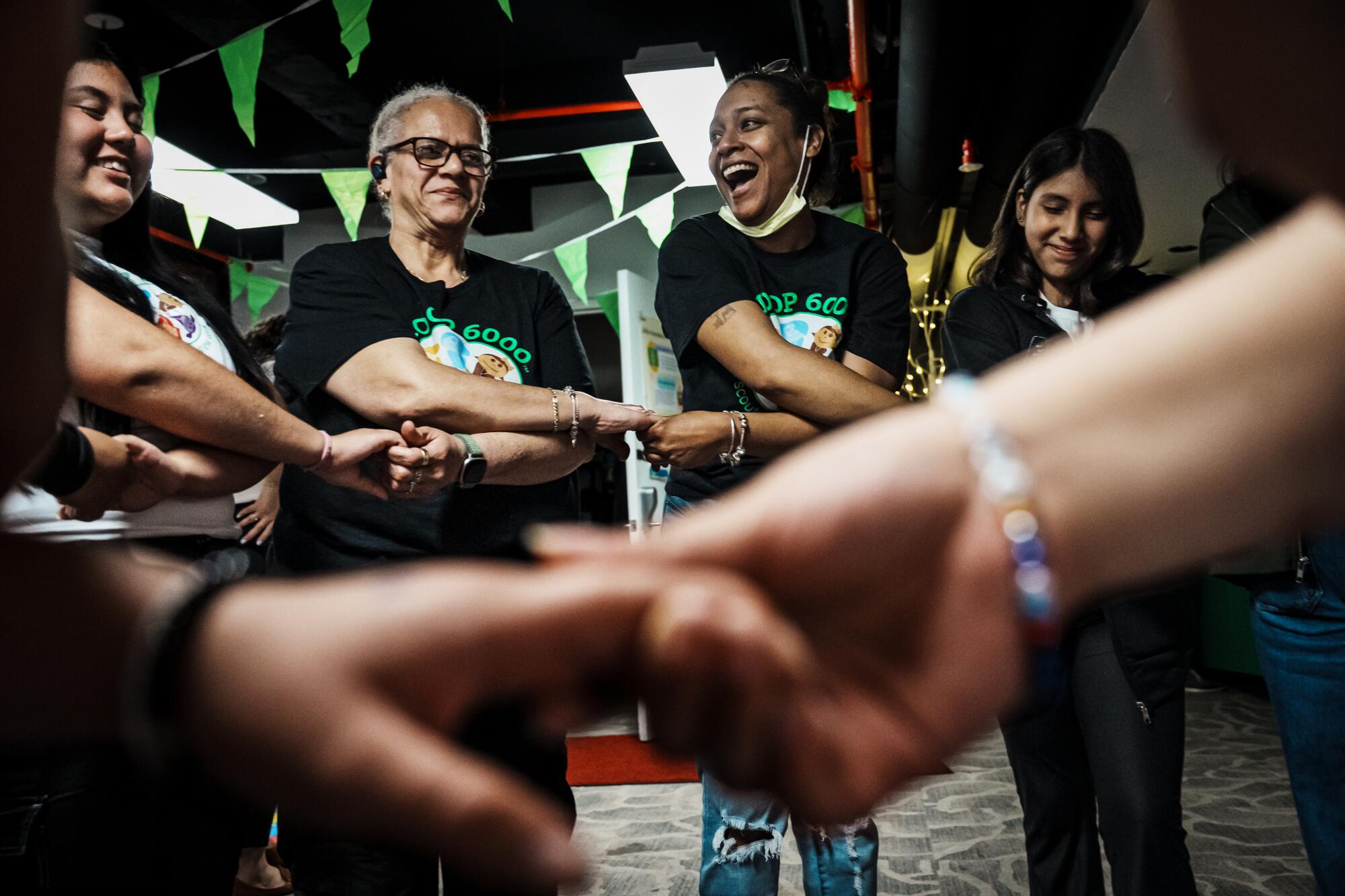 Women and girls cross their arms and hold hands in a circle. 