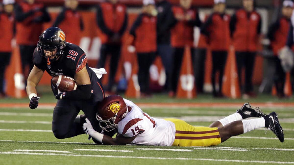 Utah tight end Evan Moeai is tackled by USC linebacker Michael Hutchings in the first half last season.