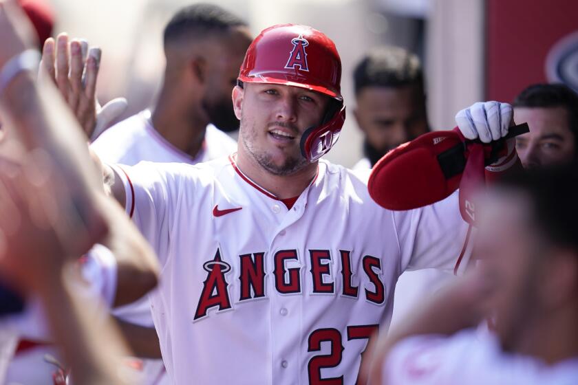 Los Angeles Angels' Mike Trout (27) celebrates in the dugout after scoring off of a single hit by Taylor Ward.