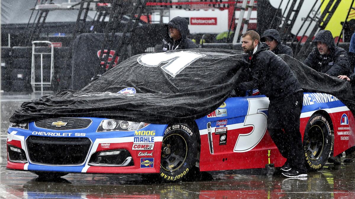 Crew members push the car of NASCAR driver Kasey Kahne through the garage area at Charlotte Motor Speedway on Friday.