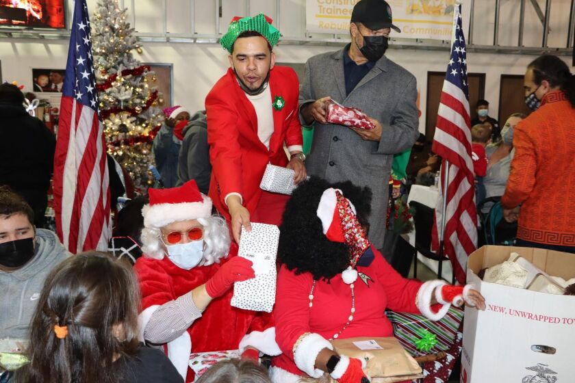Shane Harris, president of the People's Association of Justice Advocates, center, hands gifts to Santa at the 5th annual “Shane Harris Community Christmas Day Breakfast & Gift Giveaway.”