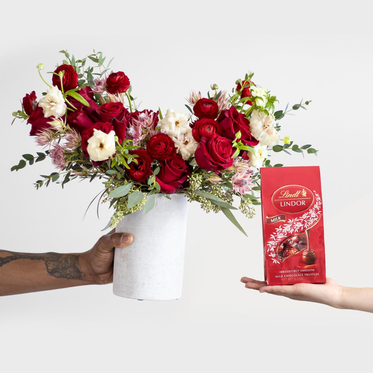 A photo of hands holding Farmgirl Flowers and Lindt Chocolates.