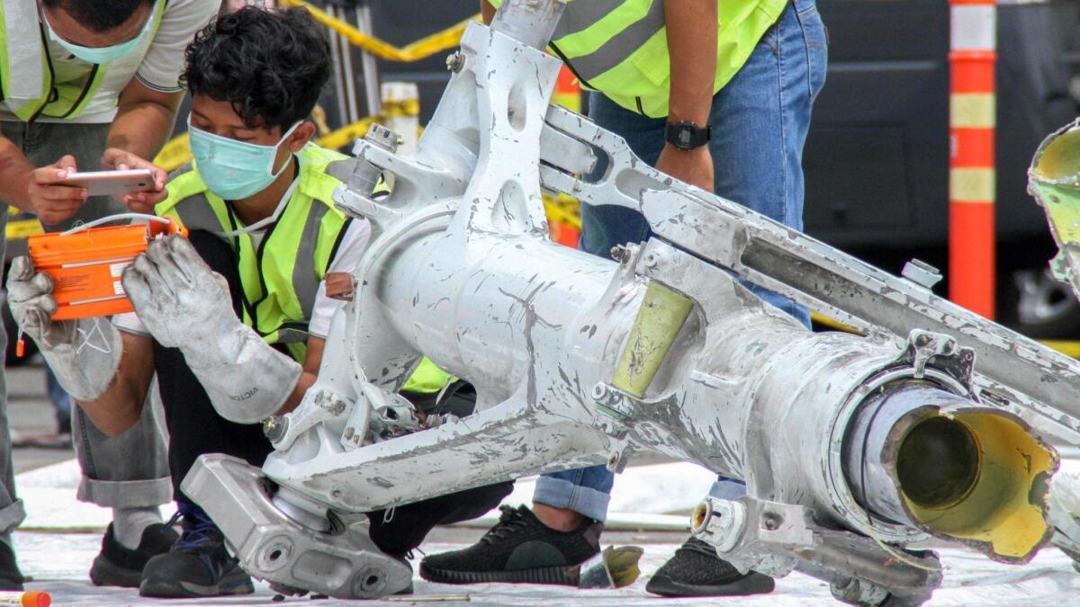 Lion Air investigators examine part of the landing gear of the ill-fated Lion Air flight JT 610 at the port in northern Jakarta on Nov. 5.