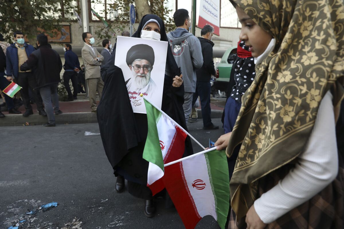 A demonstrator holds a portrait of the Iranian Supreme Leader Ayatollah Ali Khamenei as a girl holds the country's national flag in a rally in front of the former U.S. Embassy commemorating the anniversary of its 1979 seizure in Tehran, Iran, Thursday, Nov. 4, 2021. The embassy takeover triggered a 444-day hostage crisis and break in diplomatic relations that continues to this day. (AP Photo/Vahid Salemi)