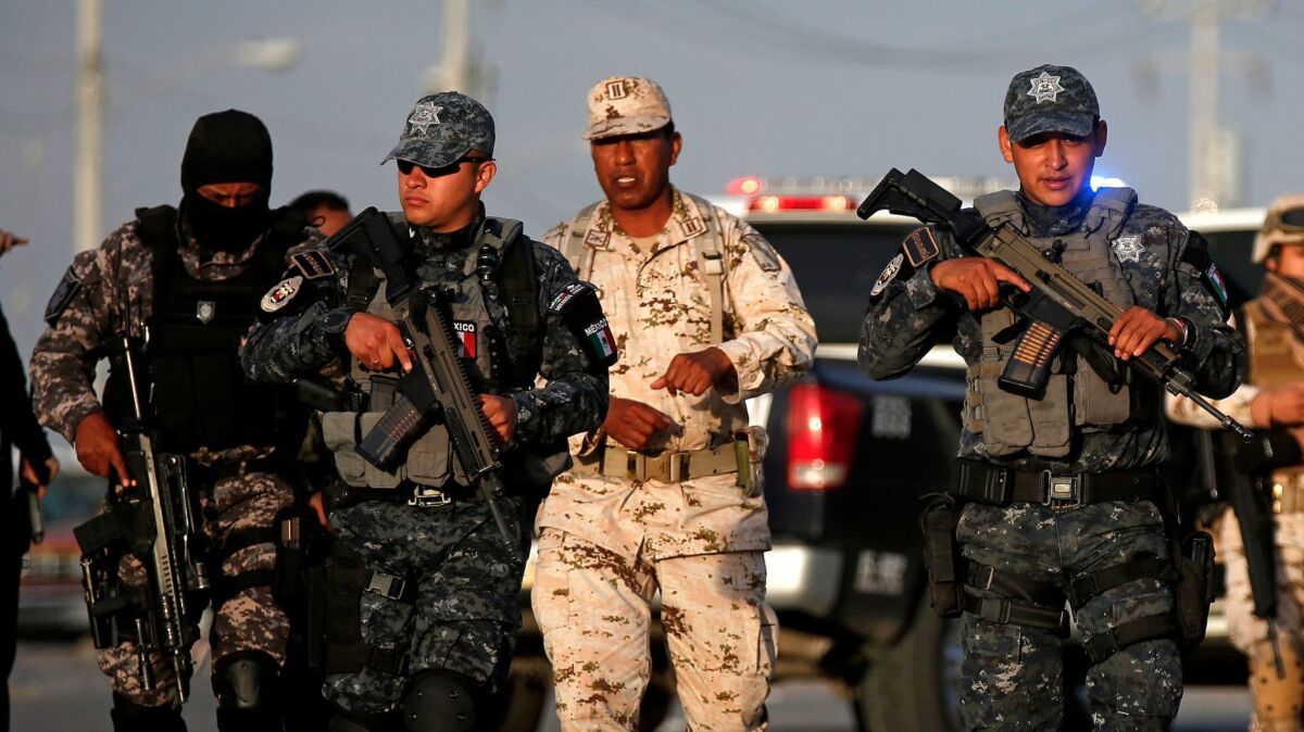 Members of the Mexican federal police and the Mexican army stand guard at the scene of a shooting in Tijuana on April 25.