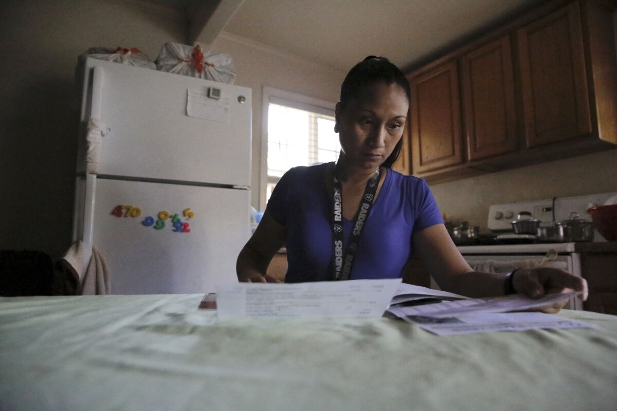 Mary Taboniar, a housekeeper at the Hilton Hawaiian Village resort in Honolulu, looks over bills at her home in Waipahu, Hawaii, Saturday, Sept. 4, 2021. Taboniar went 15 months without a paycheck, thanks to the COVID pandemic. The single mother of two saw her income completely vanish as the virus devastated the hospitality industry. Taboniar is one of millions of Americans for whom Labor Day 2021 represents a perilous crossroads. (AP Photo/Caleb Jones)