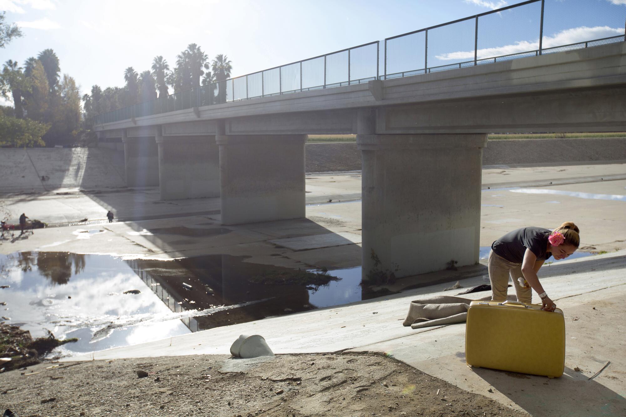 Ashley Heldman, 29, opens a suitcase she found along the L.A. River near a homeless community.