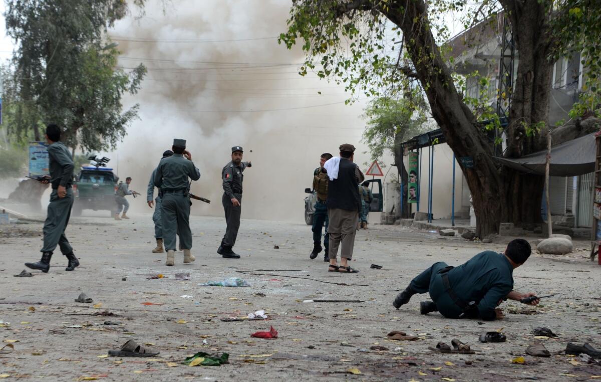 Afghan security personnel look on after a second explosion following a suicide attack outside a bank in Jalalabad on April 18, 2015.