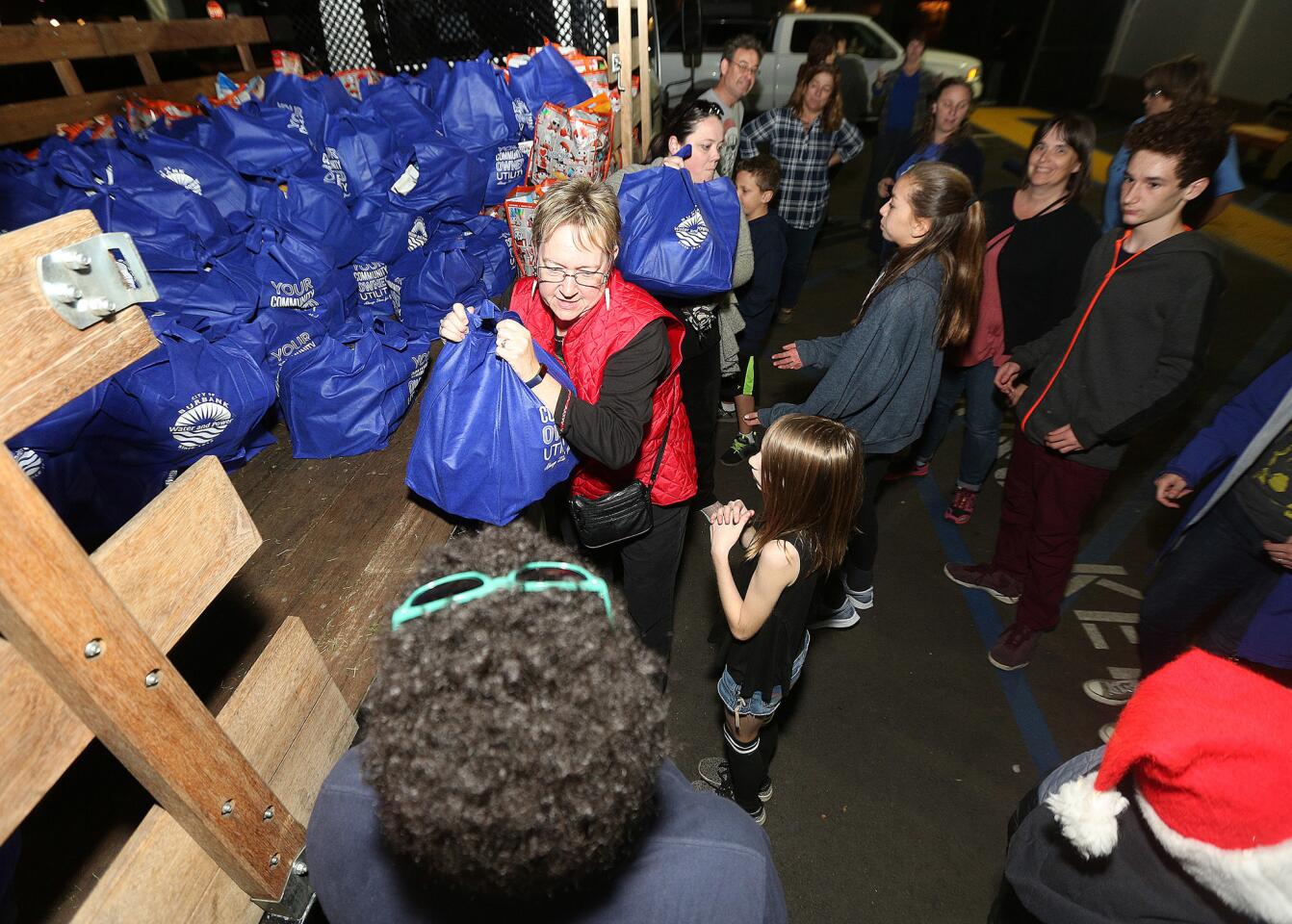 Heavy bags of food are being unloaded from a flatbed truck by dozens of volunteers at William McKinley Elementary in Burbank on Friday, December 14, 2018. Receiving donations from grocery stores, and business who conducted food drives, the Burbank Coordinating Council assembled multiple bags of food and gifts for over 500 Burbank families in need. Everything will be delivered on Saturday.